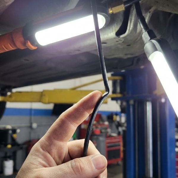 A person checking cords attached to an auto lift.